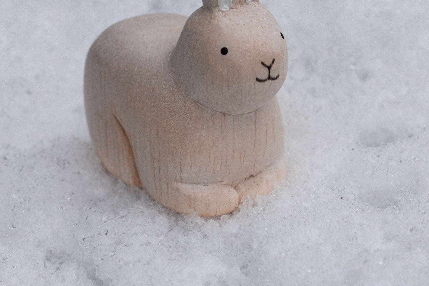 Figurine lapin en bois d'albizia T-LAB posée dans la neige